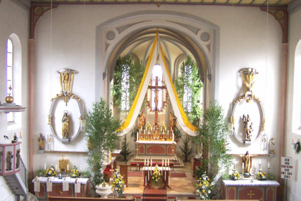 Hofkirchen - Festlich geschmckt zum Priesterjubilum 2003. Bemerkenswert ist das romanische Kreuz am Hochaltar. Dargestellt wird die Sterbeszene. Jesus lebt noch. Die Augen sind geffnet. Die Seitenwunde fehlt.